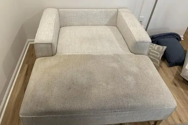 A pale fabric chaise with a soiled seat